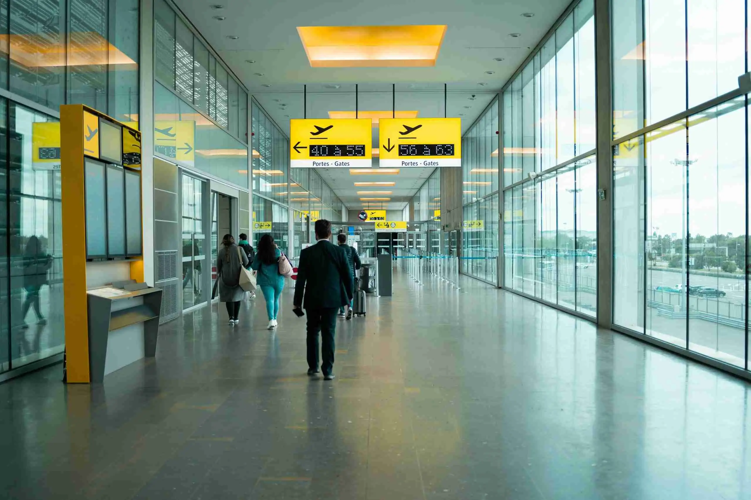 Pasajeros caminando por una terminal luminosa hacia las puertas de embarque